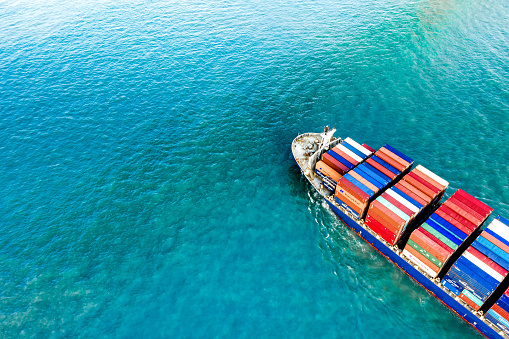 Container freight ship carrying container box for import and export business logistic and transportation by container ship in open sea, Aerial view.