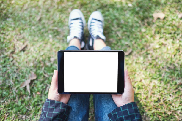 istock a woman holding and using black tablet pc with blank white desktop screen while sitting in the outdoors 1197443238