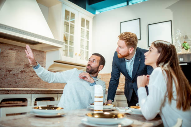 A male explaining his decor and functionality idea to his wife and sales rep in a kitchen appliances shop stock photo