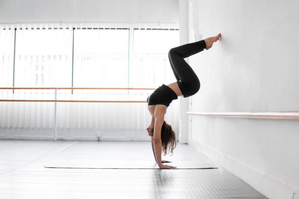 istock Woman doing a handstand in white dance studio, upside down, hand stand 1197452653