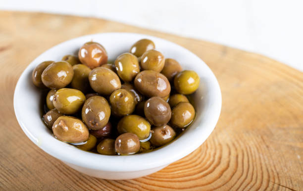 istock Green olives in white ceramic bowl on wooden board. 1197466509