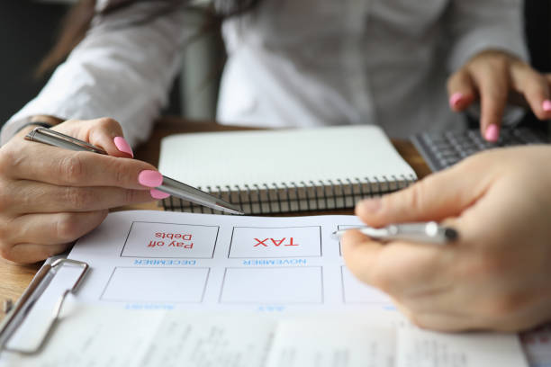 Business plan tax performing Focus on business plan with tax column. Man and woman at meeting dealing with financial issues of company. Desk with calculator and notebooks. Accounting workers of organization tax plan discution stock pictures, royalty-free photos  images