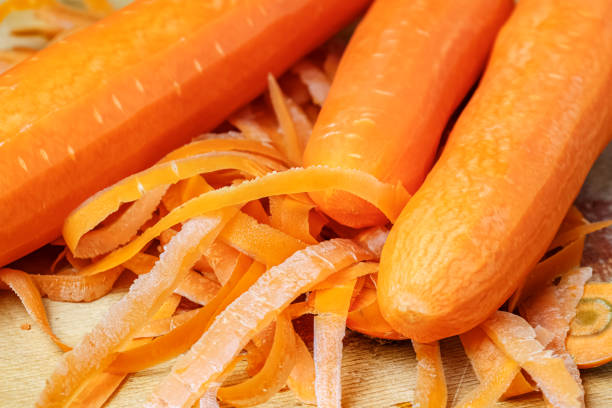 Fresh juicy carrots with removed skin on the wooden cutting board close-up Fresh juicy carrots with removed skin on the wooden cutting board close-up peeled photos stock pictures, royalty-free photos & images