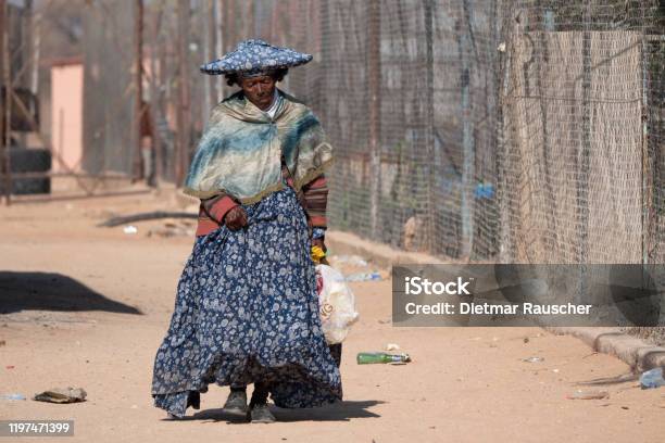 Photo libre de droit de Pauvre Vieille Femme Dherero Utilisant La Robe Traditionnelle Et Le Chapeau De Corneshaped Marchant banque d'images et plus d'images libres de droit de Adulte