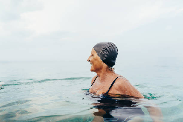 seniorschwimmerin im meer - badeanzug stock-fotos und bilder