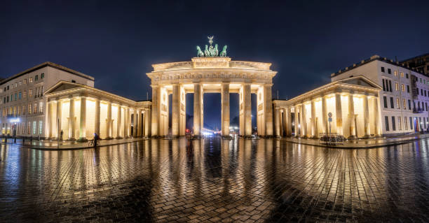 Panoramic view of the Brandenburg Gate in Berlin, Germany, during night Panoramic view of the Brandenburg Gate in Berlin, Germany, during night with a cloudy sky and wet grounds with reflections brandenburg gate photos stock pictures, royalty-free photos & images