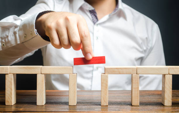 um homem está completando a construção de uma ponte. construir pontes, fazer conexões e contatos úteis. melhorar e desenvolver um negócio. novas soluções inovadoras, crescimento e prosperidade - ponte - fotografias e filmes do acervo