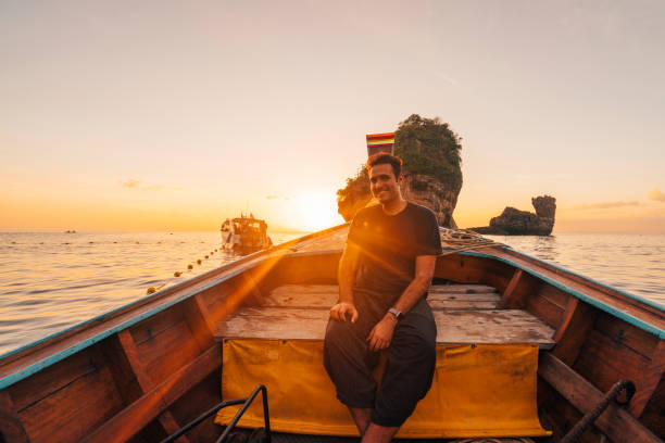 Young man on a longtail boat in Thailand during sunset, Phi Phi Island