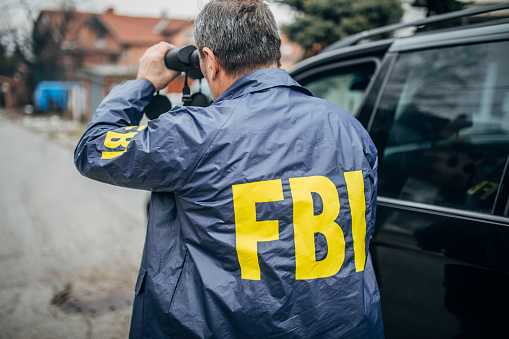 An FBI agent uses binoculars