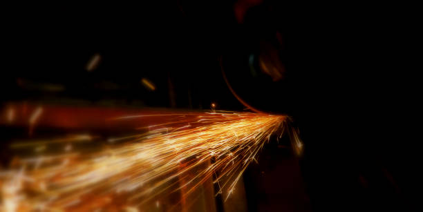 el flujo brillante de partículas de chispa de acero o metal brillan en el fondo oscuro. soldador en taller de fabricación de construcción de metal mediante el corte a la forma utilizando enormes chispas naranjas. metal de aserrado artesano con molinillo - industrial ship flash fotografías e imágenes de stock