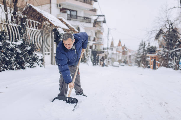 un hombre limpia la acera de la nieve frente a su casa - thick snow fotografías e imágenes de stock