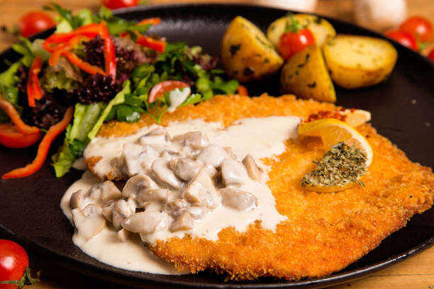 Mushroom sauce homemade Schnitzel. Homemade Breaded German Weiner Schnitzel with Potato.\nHorizontal composition, studio shot, indoors shot.
