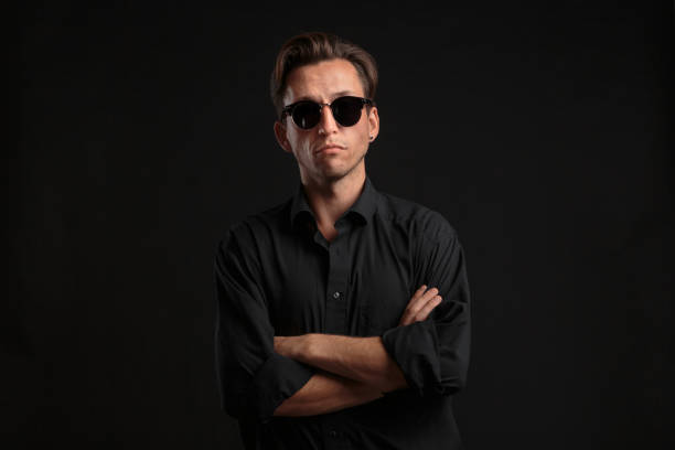 istock Confident stylish man in black eyeglasses isolated over black background. 1197485055