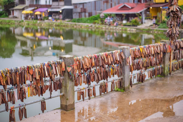 étiquettes de prière attachées sur le pont dans le village de mine de pilok dans la ville de kanchanaburi en thaïlande. - asia kanchanaburi province lake nature photos et images de collection