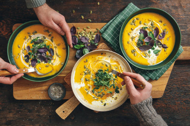 hommes mangeant la soupe crémeuse de citrouille rôtie végétalienne - repas servi photos et images de collection