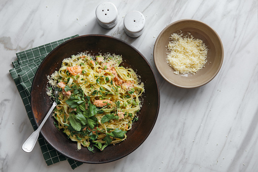 Creamy Salmon Pasta with mint peas on marble background. Top view.