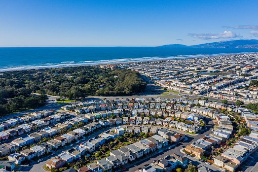 An aerial view of Outer Sunset in San Francisco on a sunny day. Colorful row houses in ocean development with the coast line visible.