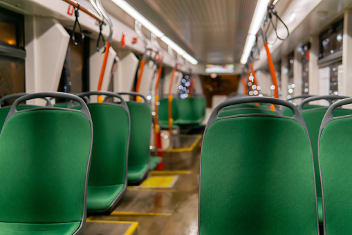 partially blurred interior of a low - floor tram cabin with rows of chairs in the foreground