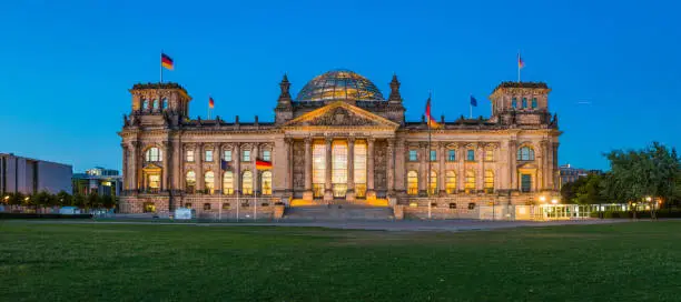 The iconic facade of the Reichstag, home of the Bundestag, German Parliament, illuminated at dusk in the heart of Berlin, Germany’s vibrant capital city.