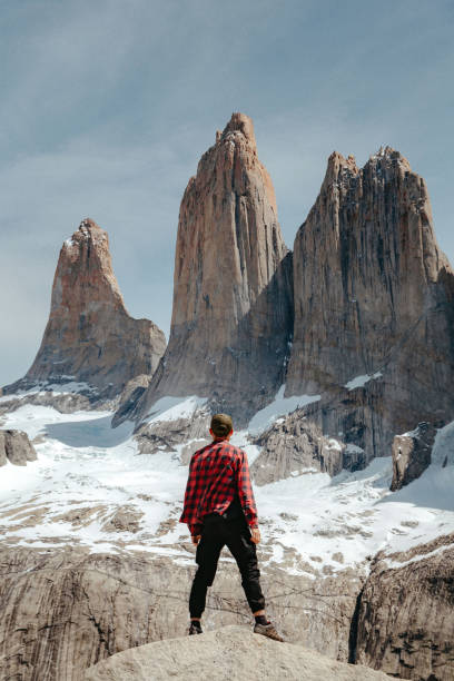 un homme se tient sur un rocher et regarde mirador base las torres dans le parc national de torres del paine - european alps mountain mountain peak rock photos et images de collection