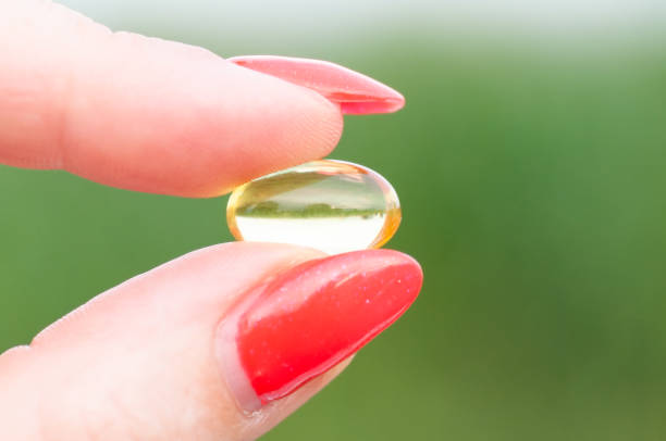 istock Yellow and transparent pill held between thumb and finger 1197509531