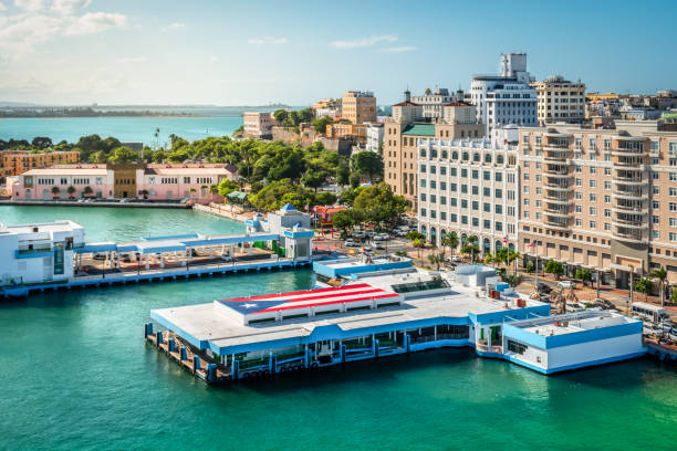 Port of San Juan, Puerto Rico. Colorful image of the cruise and ferry harbor of San Juan in Puerto Rico. Puerto Rican flag on platform above the water pier. Tall buildings at the cruise port terminal. puerto rico photos stock pictures, royalty-free photos & images
