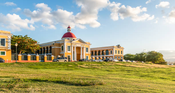 Colorful image with public art school. Blue sky, white clouds, yellow building and green grass.