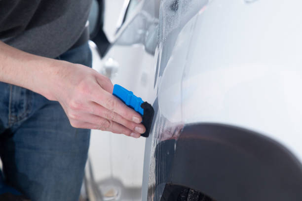 istock Installing a protective film on the car body 1197520375