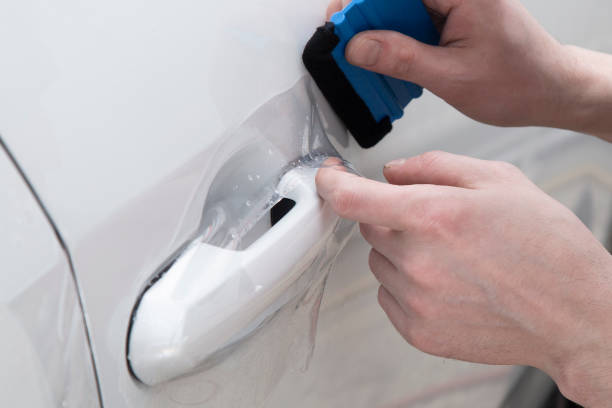 istock Installing a protective film on the car body 1197520442