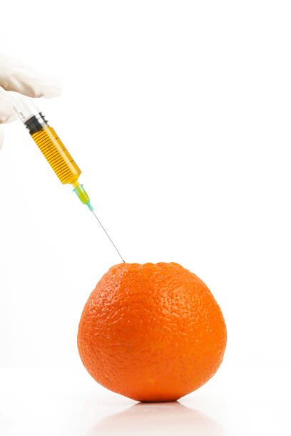 istock Closeup of needle injected into orange, Genetically engineered food concept 1197521373