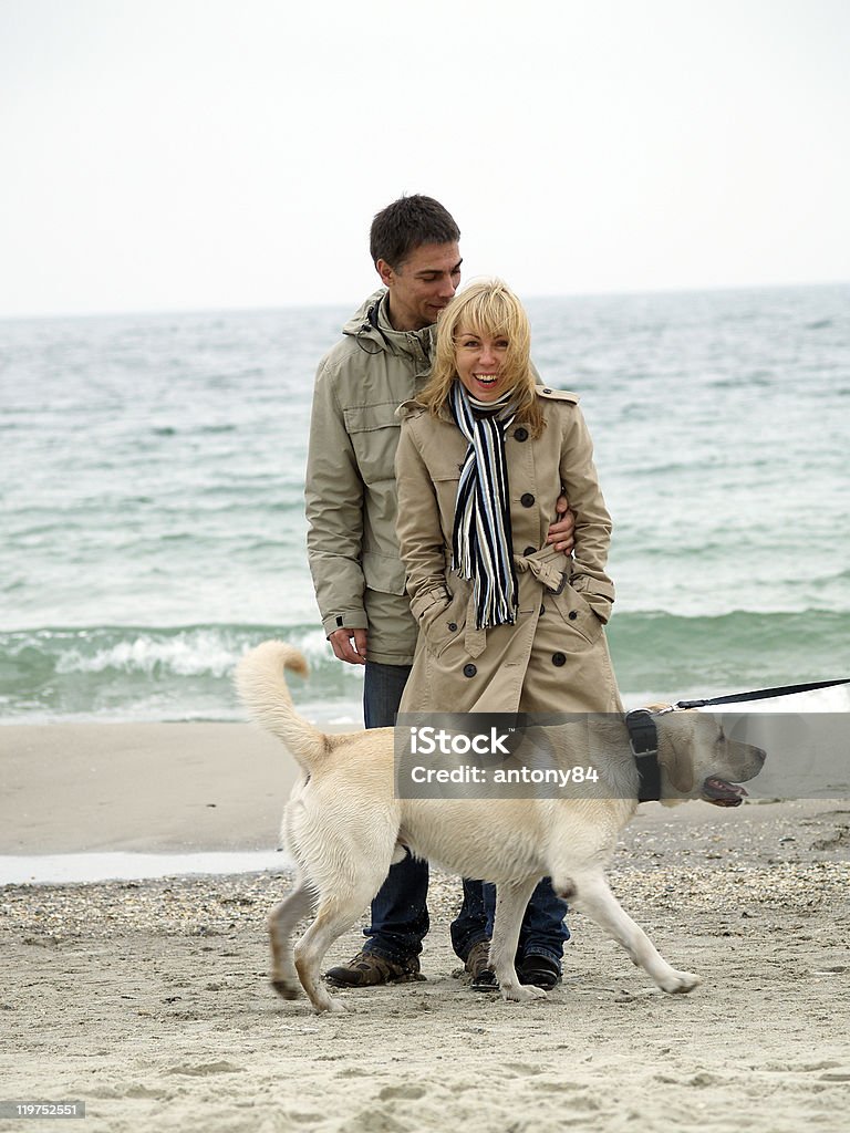 Mid aged couple with dog on sea shore  Beach Stock Photo