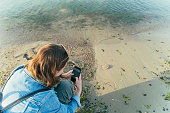 Young solo traveller taking pictures of jellyfish with a smartphone on the beach