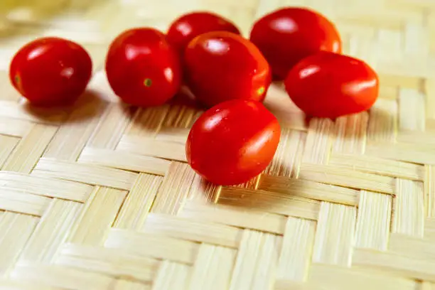 many red ripe and juicy cherry tomatoes close-up on a wooden background