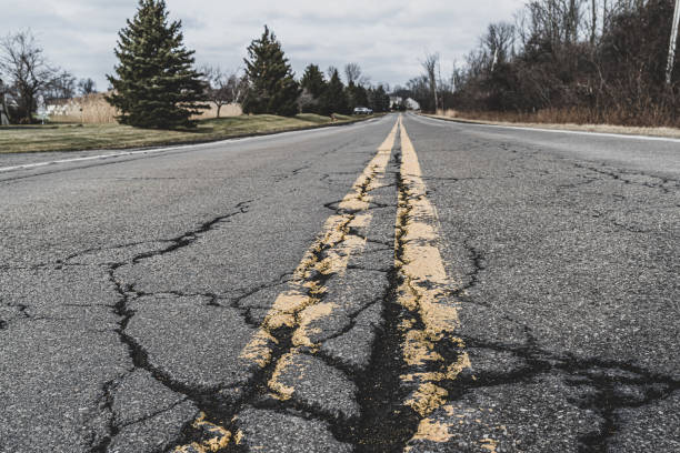 закрыть дорожную разметку и треснувший асфальт пригородной дороги - autumn landscape usa country road стоковые фото и изображения