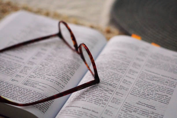 A thick book and glasses in a low light room, glasses on a book