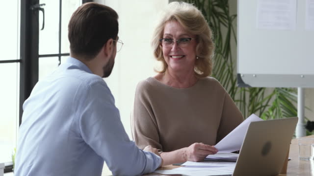 Businessman manager consulting happy old businesswoman customer explain contract benefits