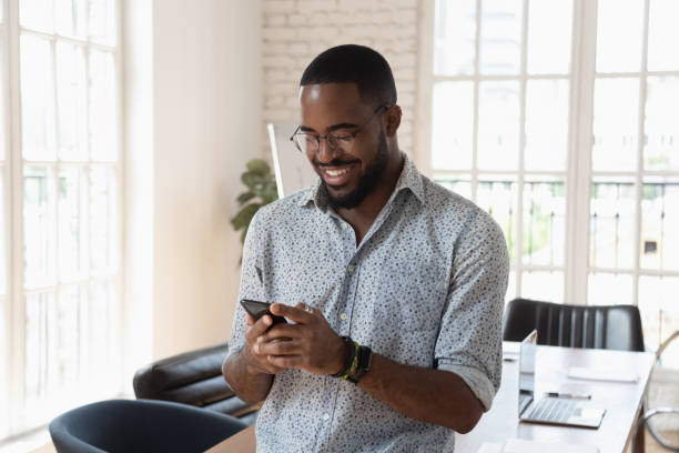 istock Positive young african businessman using smartphone at workplace 1197547364