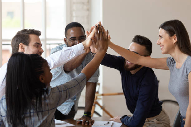 istock Excited multinational employees celebrating team victory giving high five 1197547421