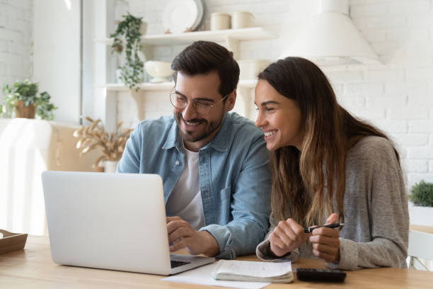 felice giovane coppia pagare le bollette online in app per computer - economia familiare foto e immagini stock
