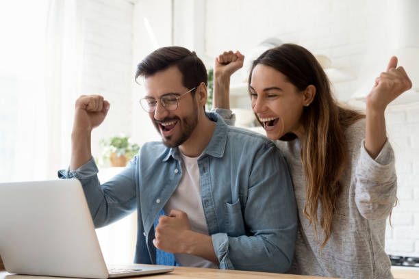 istock Excited young couple using laptop celebrate online win together 1197547540