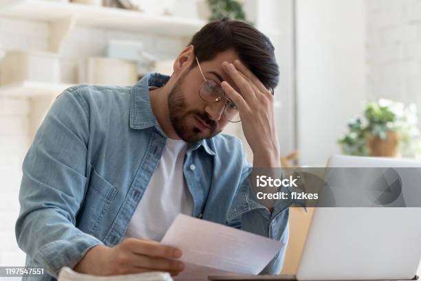 Upset Frustrated Young Man Holding Reading Postal Mail Letter Stock Photo - Download Image Now