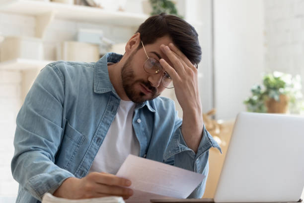 upset frustrated young man holding reading postal mail letter - frustration computer confusion businessman imagens e fotografias de stock