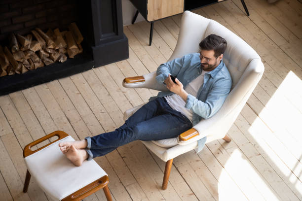 istock Relaxed guy sit on comfortable chair in house using phone 1197547553