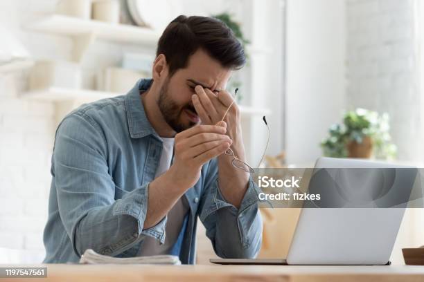 Tired Young Man Feel Eyestrain Holding Glasses Fatigued From Computer Stock Photo - Download Image Now