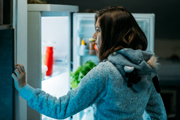 istock Young girl at night in front of a refrigerator 1197547657