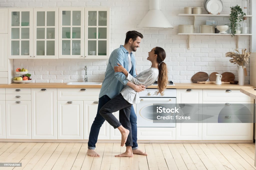 Feliz pareja romántica bailando en la cocina moderna en casa - Foto de stock de Parejas libre de derechos