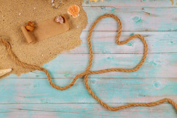 Heart made from rope on seashore with shells. Valentine day concept. Papyrus from the glass bottle with cork.