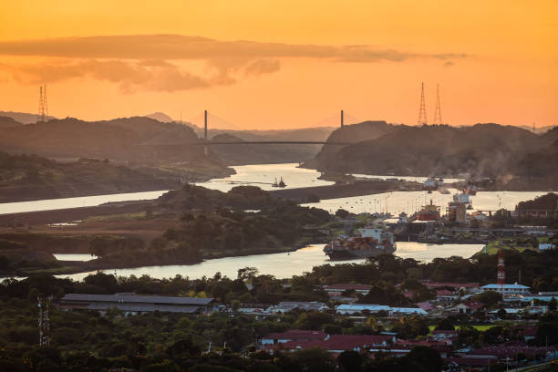 container ship passing through panama canal in scenic landscape at sunset - panama canal panama mountain sunset imagens e fotografias de stock