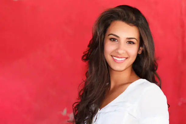 Beautiful young mixed race woman outdoor fashion portrait with a red background.