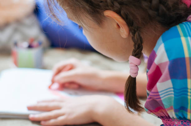 istock cute little girl drawing pictures while lying on bed 1197578312